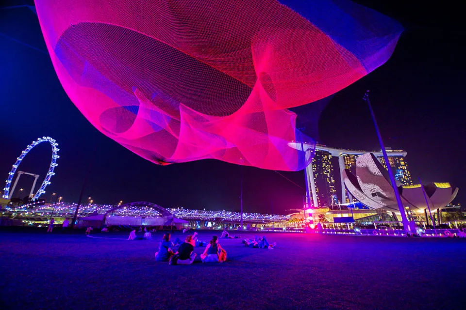 Pink light art installation above public plaza in Singapore by Janet Echelman.